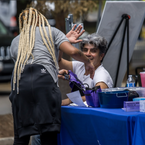 A woman reading a man's blood pressure at a tabling event.