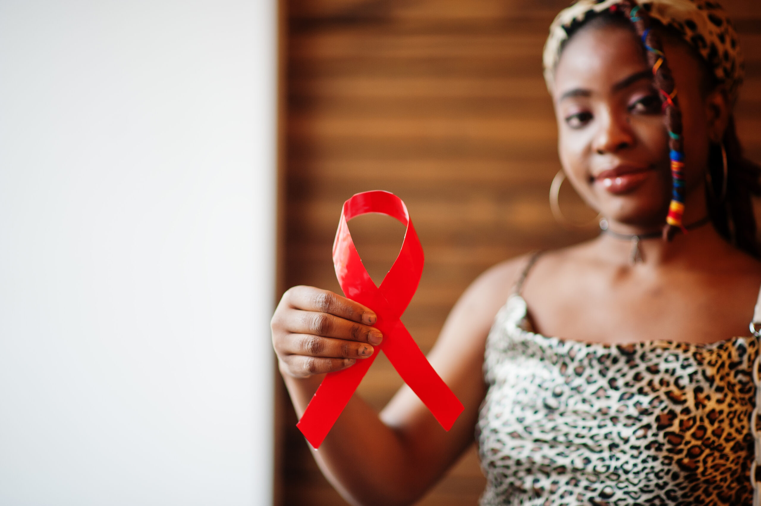African woman AIDS awareness. Stylish african american woman hold red ribbon.