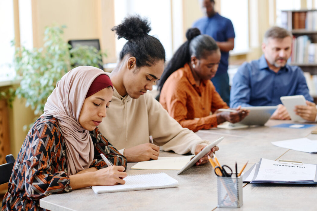 A group of diverse professionals writing at a table during training.