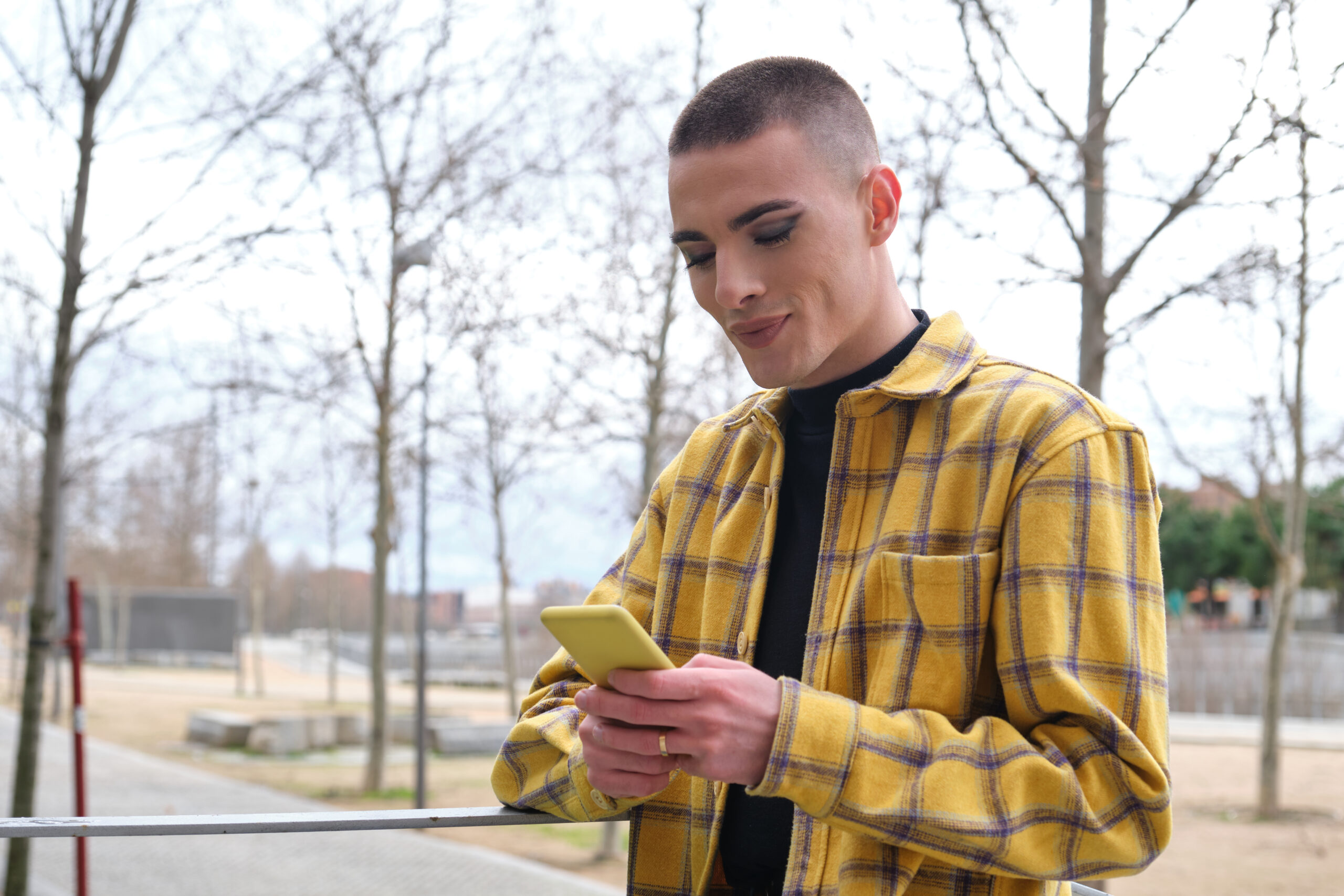 Young,Non,Binary,Person,Checking,His,Smartphone,And,Smiling.,Make