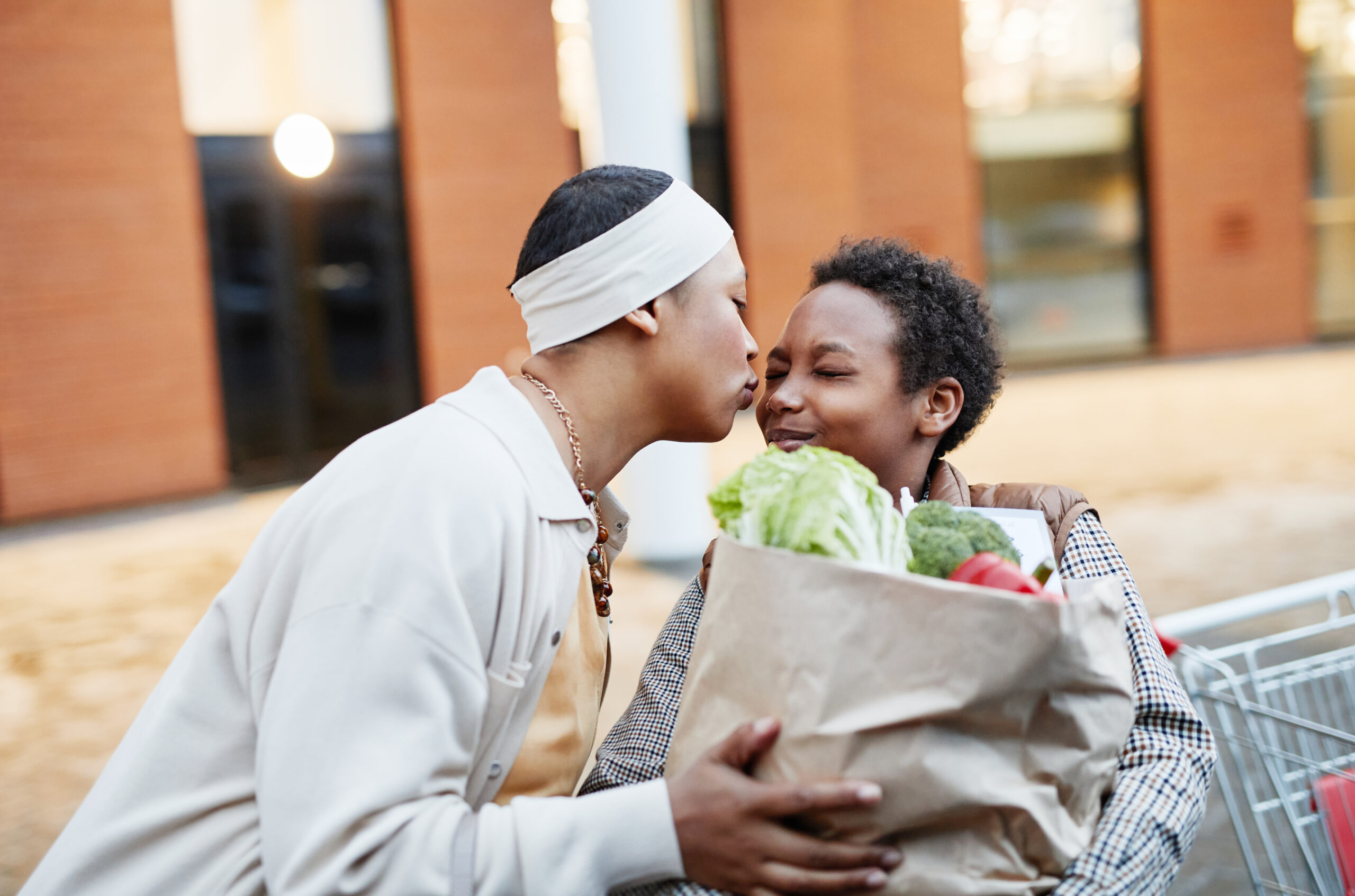 Prince George's County Food Equity Council Mom kissing son on the cheek as he helps with groceries.