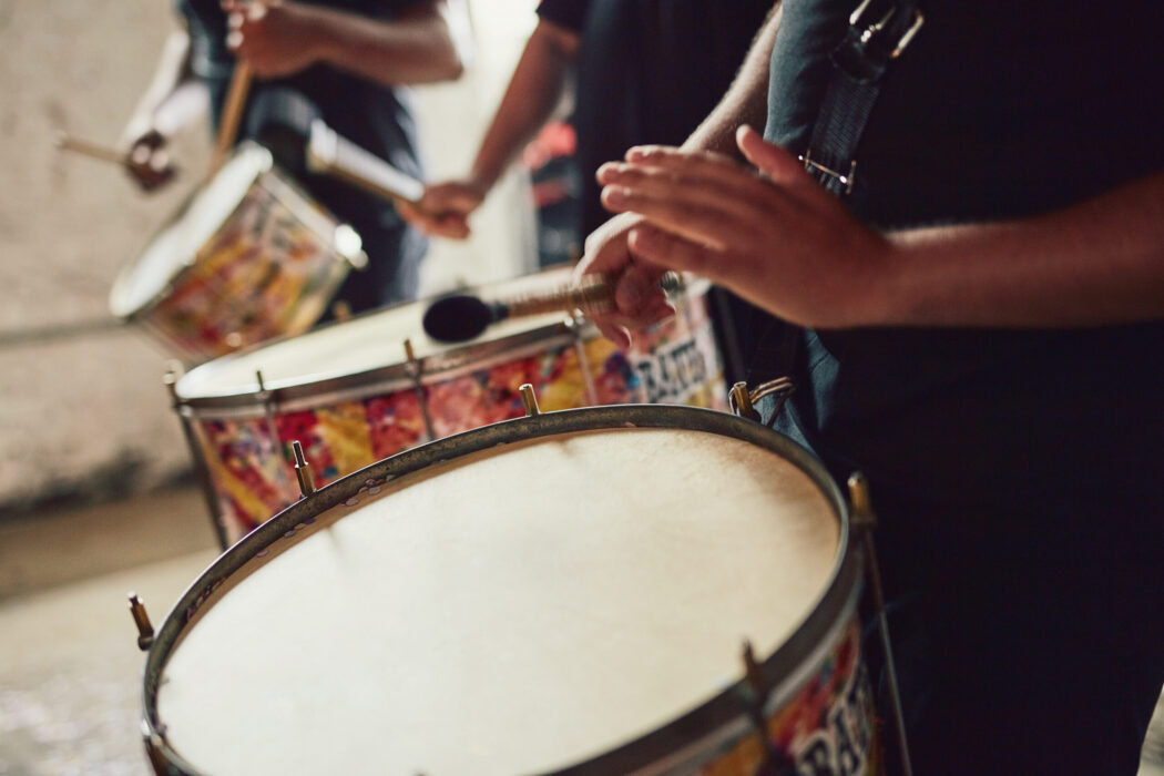Closeup shot of a musical performer playing drums with his band.